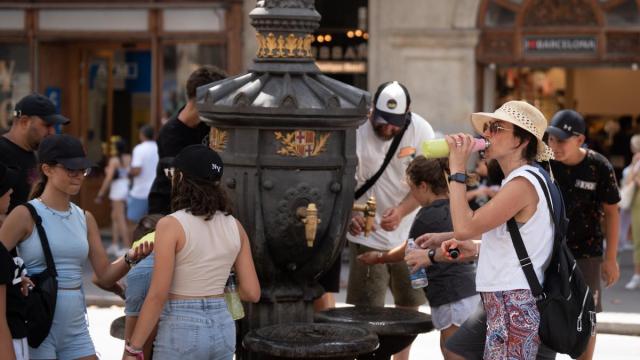 Personas se hidratan en una fuente de Barcelona durante una ola de calor