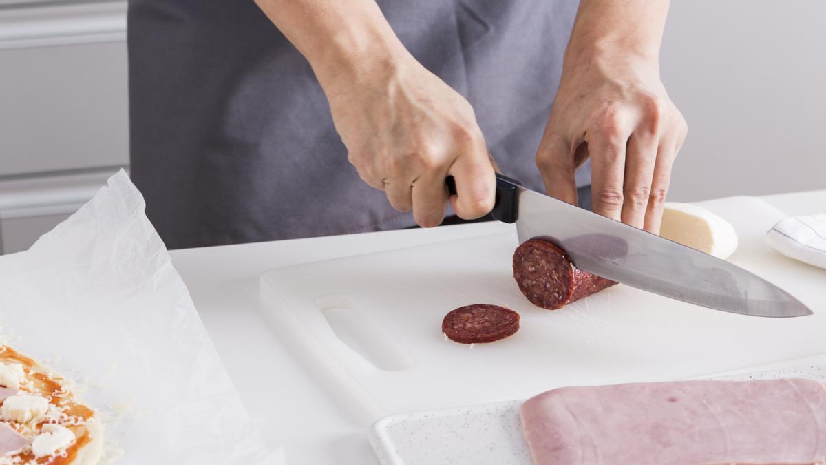 Cortar chorizo y jamón york para añadir a una pizza casera