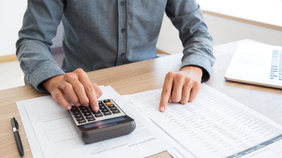 Hombre gestiona su dinero y calcula los gastos del mes con ayuda de la calculadora