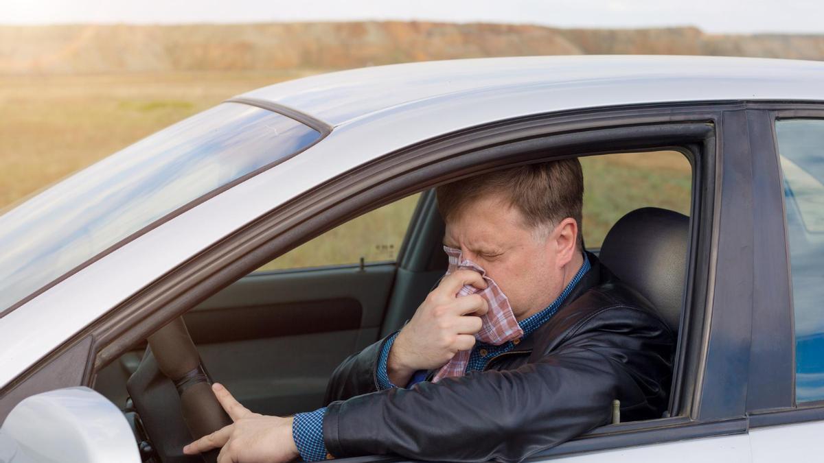 Un hombre se suena la nariz dentro del coche.