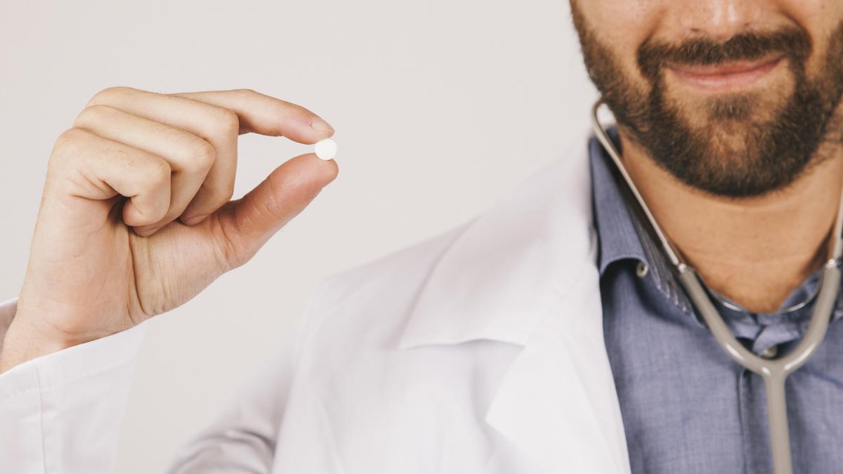 Médico sosteniendo una pastilla