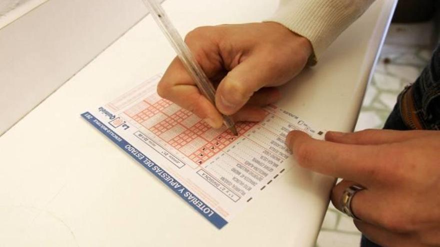 Un apostante rellena una quiniela en una Administración de Lotería
