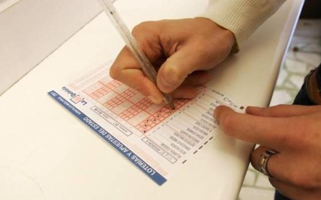 Un apostante rellena una quiniela en una Administración de Lotería