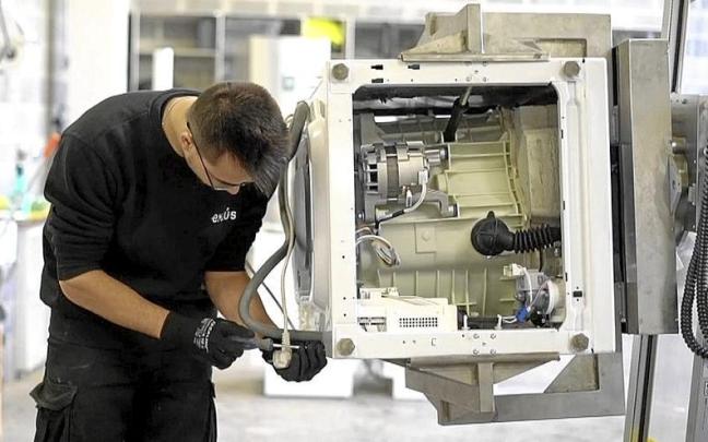 Un trabajador monta piezas de una lavadora.