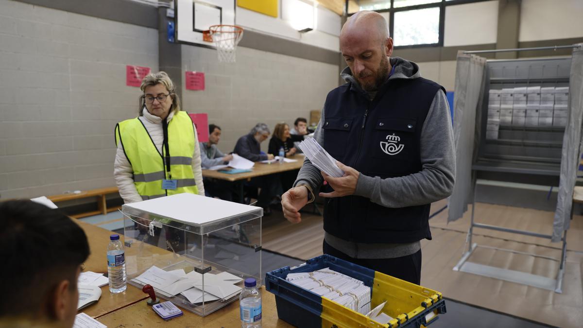 Un empleado de correos entrega votos por correo en una mesa electoral.