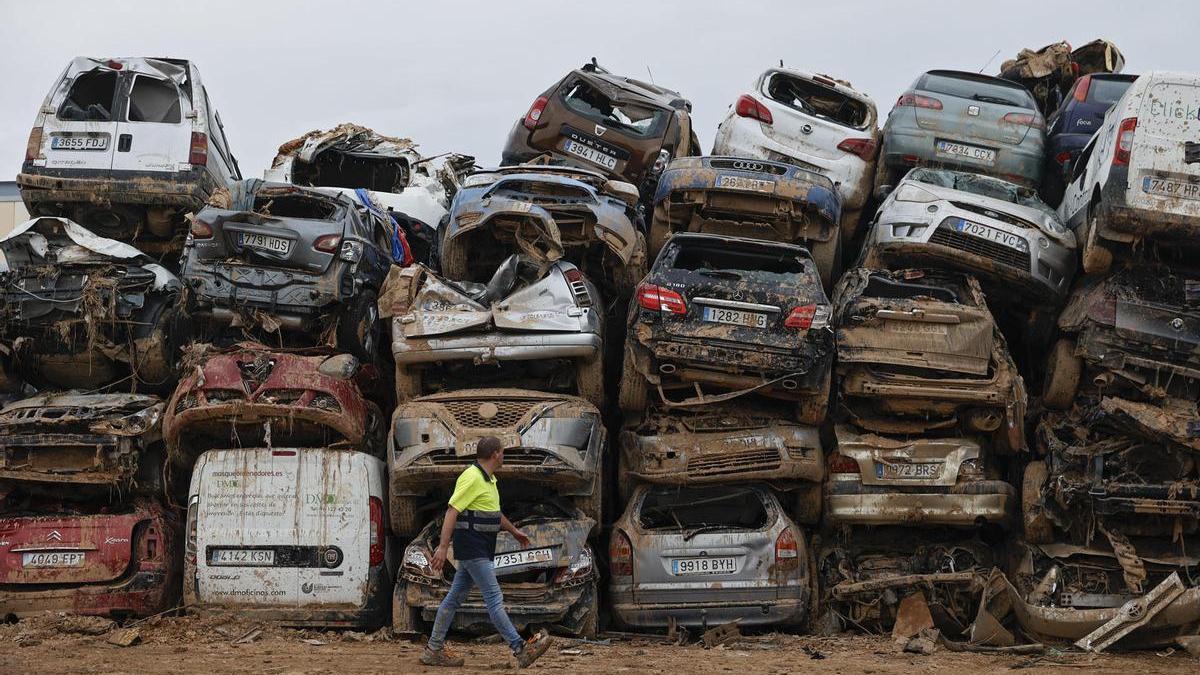 Varios coches que fueron arrastrados por el agua tras el paso de la DANA, almacenados en un descampado en Paiporta.