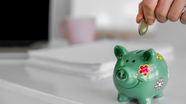 Una persona introduce una moneda de euro en una hucha.