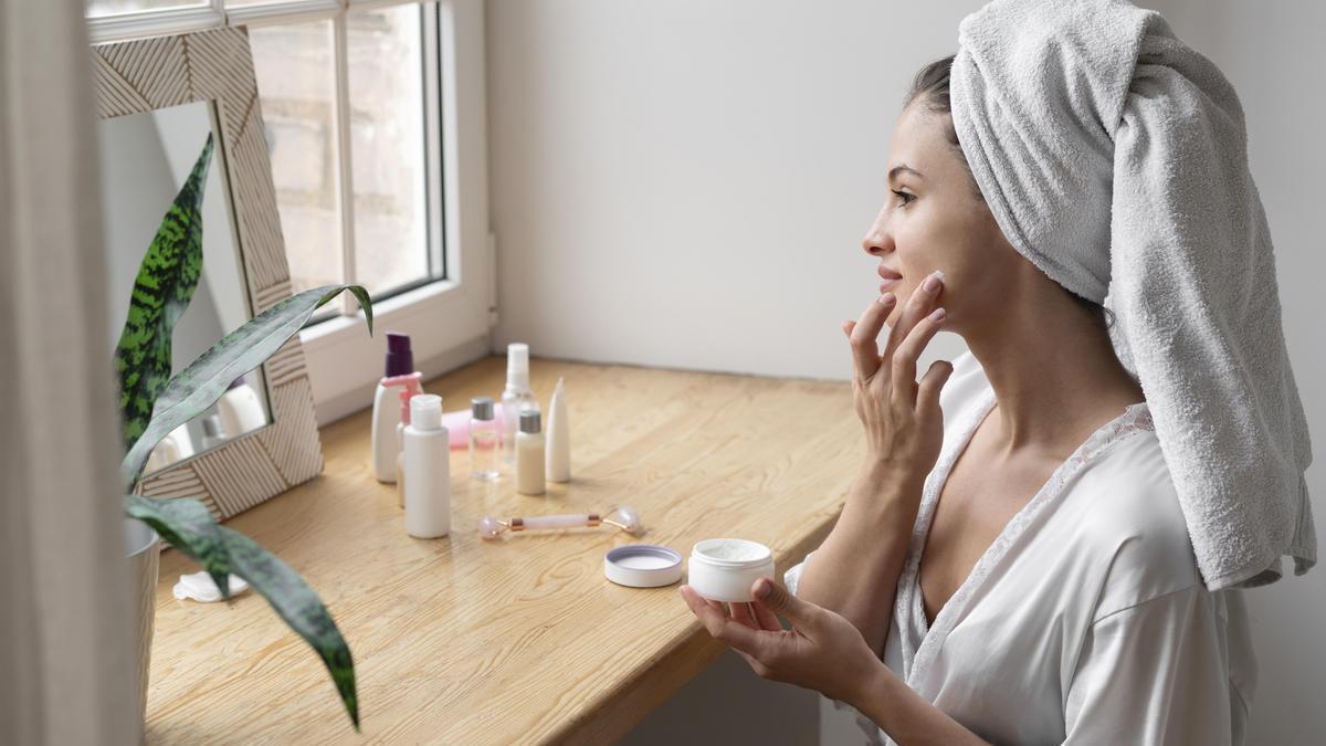 Mujer joven aplica su rutina de cuidado facial en casa nada más salir de la ducha.