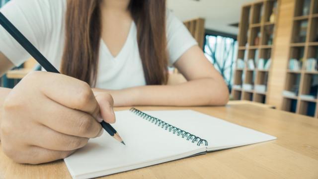 Una alumna coge apuntes en un cuaderno.