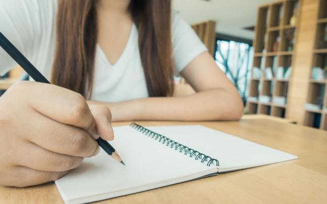 Una alumna coge apuntes en un cuaderno.