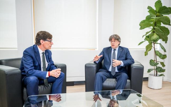 El presidente de la Generalitat, Salvador Illa (i), saluda al presidente de Junts per Catalunya, Carles Puigdemont (d), durante su reunión en Bruselas.
