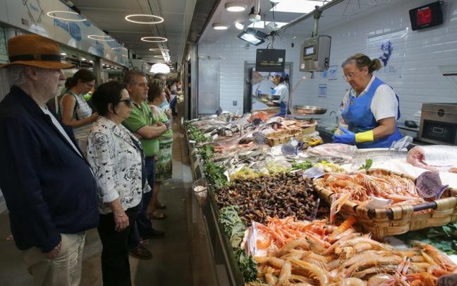 Varias personas compran alimentos en un mercado