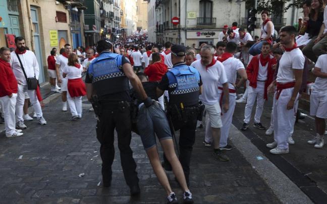 Agentes municipales retiran a un joven en estado ebrio del recorrido del encierro.