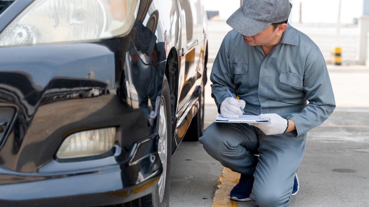 Un mecánico inspecciona un coche.