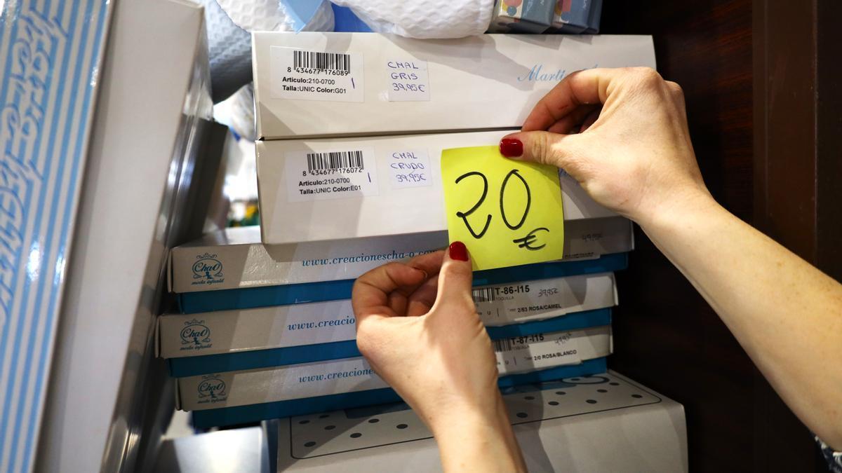 Una mujer pone una etiqueta de 20 euros en uno de sus productos.