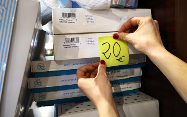 Una mujer pone una etiqueta de 20 euros en uno de sus productos. Una mujer pone una etiqueta de 20 euros en uno de sus productos.