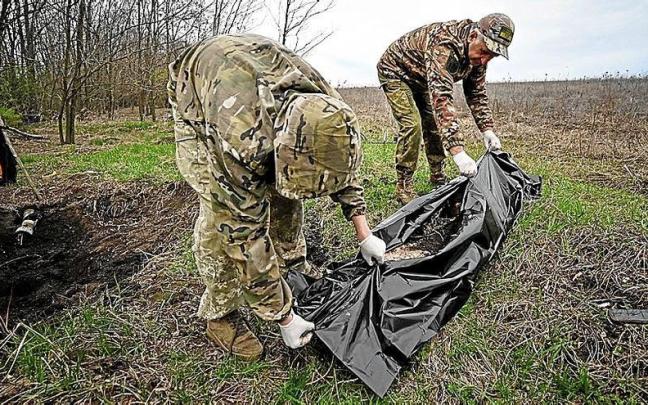 Soldados ucranianos recogen el cuerpo de un militar ruso enterrado en Járkov.
