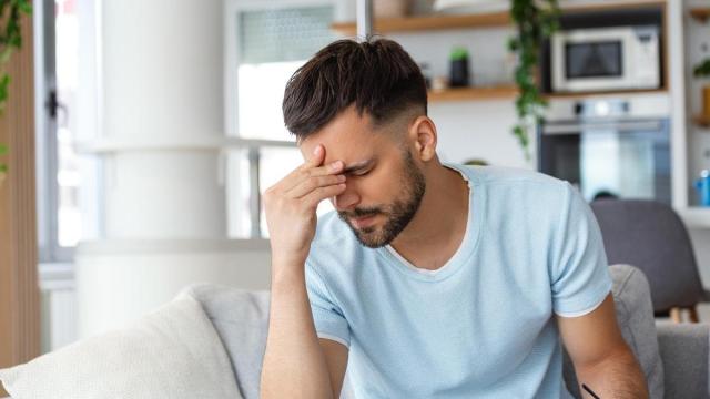 Un hombre con dolor de cabeza se lleva la mano a la frente.