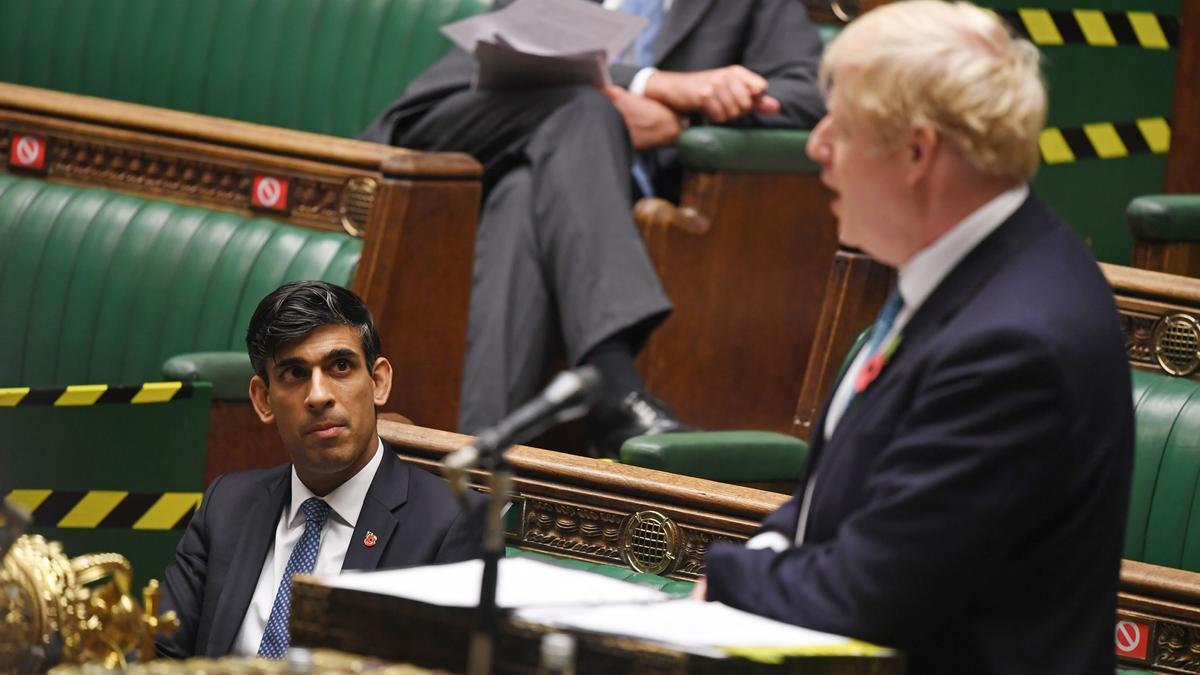 Sunak escucha a Boris Johnson en la Cámara de los comunes.