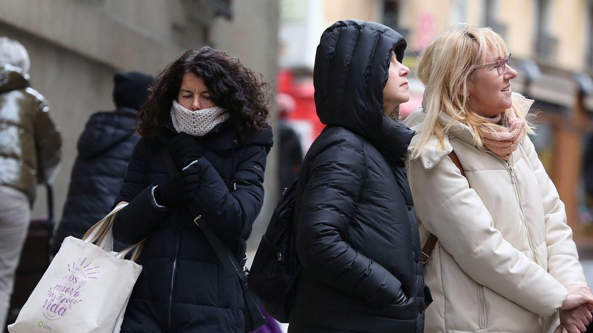 Abrigándose ante las bajas temperaturas de este martes en el centro de Pamplona.