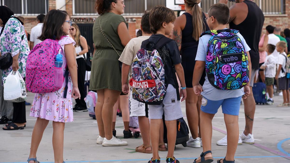 Niños esperan a la entrada de un colegio.