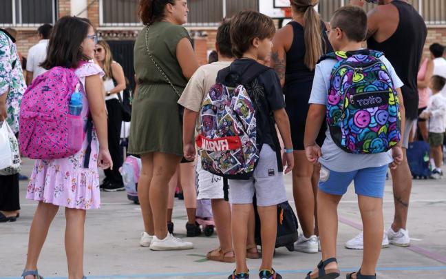 Niños esperan a la entrada de un colegio.