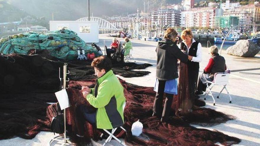 Un grupo de rederas repara las artes de pesca en el puerto de Ondarroa.