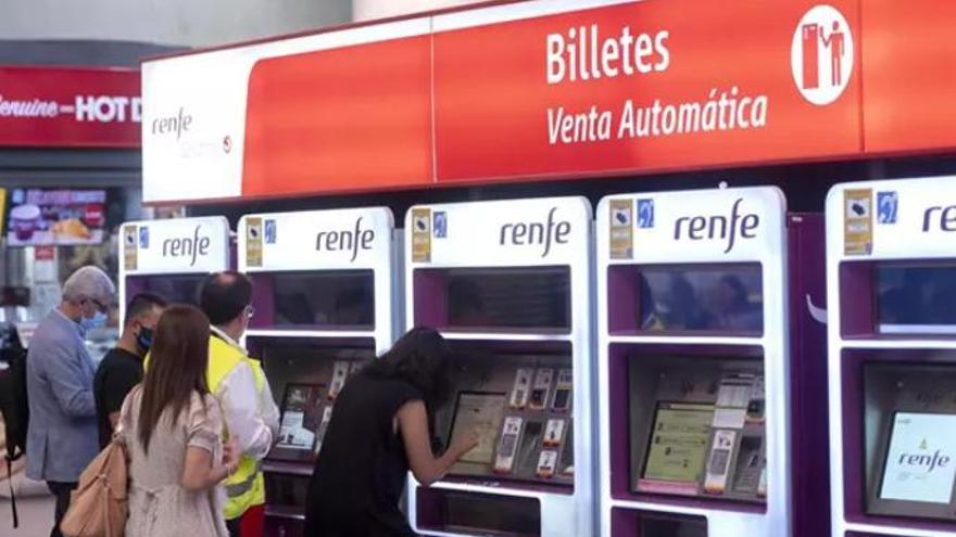Varias personas adquieren sus billetes en las taquillas de venta automática de la estación de tren de Atocha.