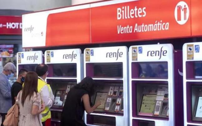Varias personas adquieren sus billetes en las taquillas de venta automática de la estación de tren de Atocha.