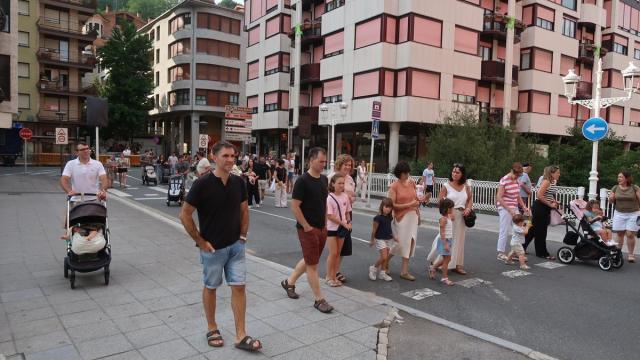 Vecinos cruzando de un lado al otro del barrio, en la kalejira de los gigantes y los dulzaineros.