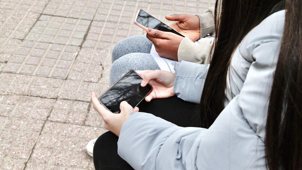 Jóvenes con sus teléfonos móviles en las manos