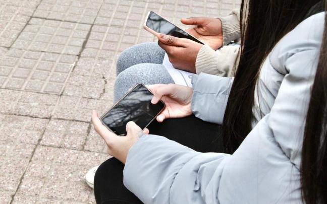 J&oacute;venes con sus tel&eacute;fonos m&oacute;viles en las manos