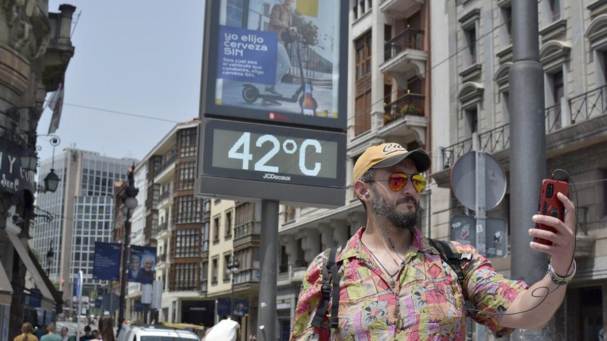 Un chico se hace un selfie delante de un termómetro de calle en la calle Navarra.