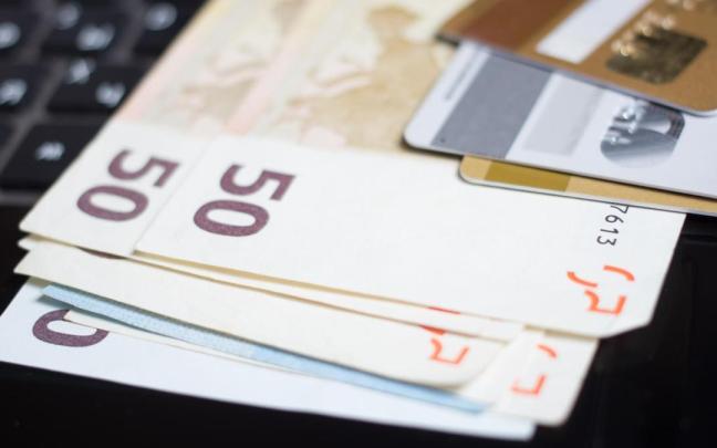 Billetes de euro y tarjetas bancarias sobre el teclado de un ordenador.