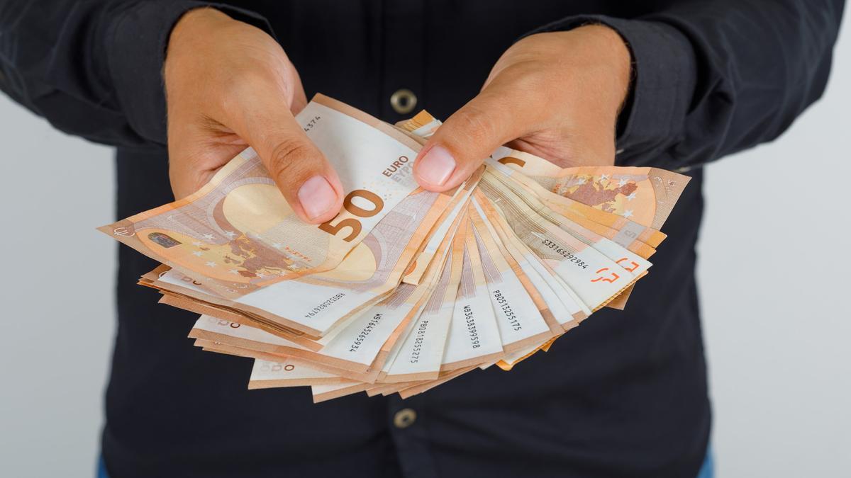 Una persona, con varios billetes de 50 euros en un sobre.