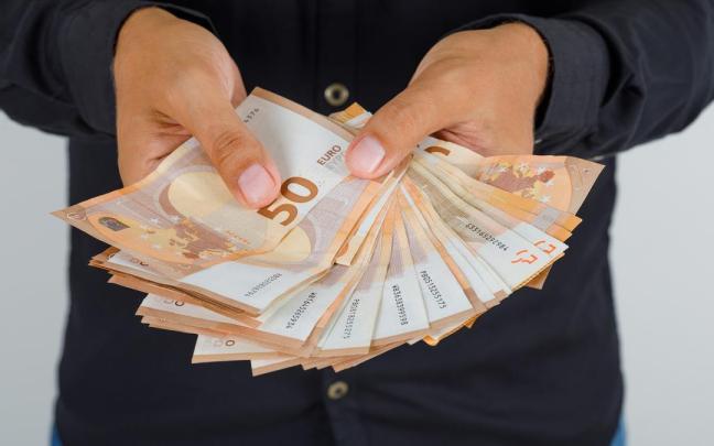 Una persona, con varios billetes de 50 euros en un sobre. Una persona, con varios billetes de 50 euros en un sobre.