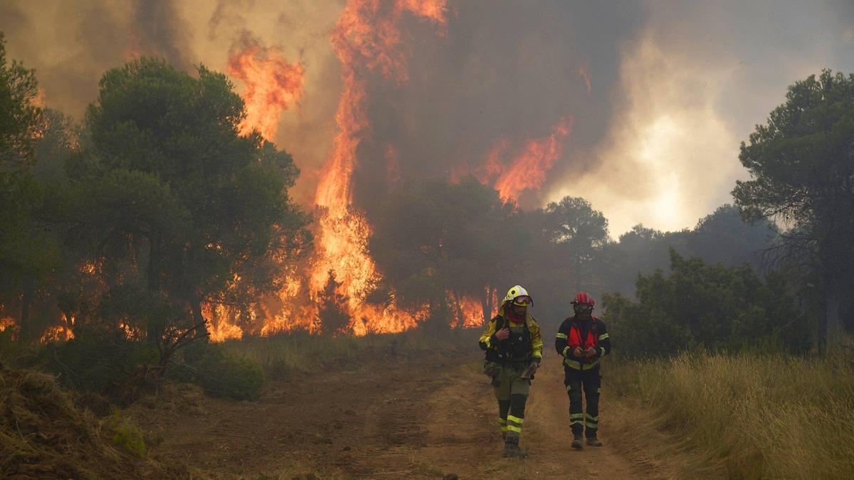Fotos del incendio forestal cerca de Carcastillo. En la imagen, dos bomberos con las grandes llamas a sus espaldas. Iñaki Porto