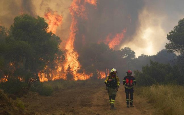 Fotos del incendio forestal cerca de Carcastillo. En la imagen, dos bomberos con las grandes llamas a sus espaldas. Iñaki Porto