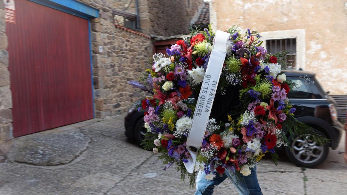 Un hombre entrega una corona de flores en la vivienda de Sánchez Dragó en Castilfrío de la Sierra.