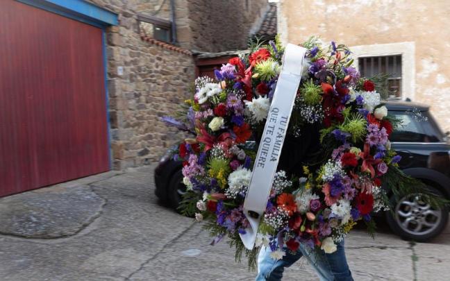 Un hombre entrega una corona de flores en la vivienda de Sánchez Dragó en Castilfrío de la Sierra.