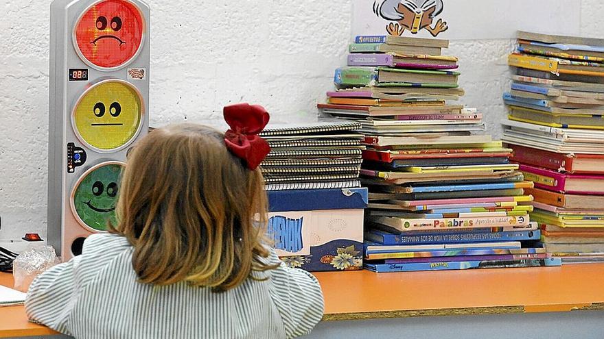 Una niña delante de juguetes y libros en un aula.