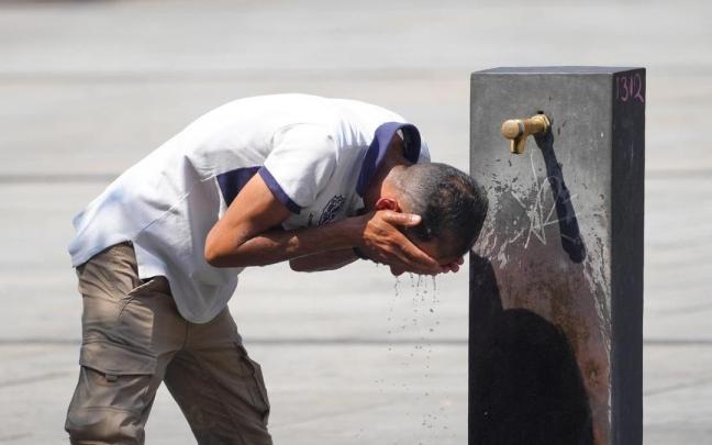Un hombre refrescándose en una fuente durante la ola de calor de agosto.