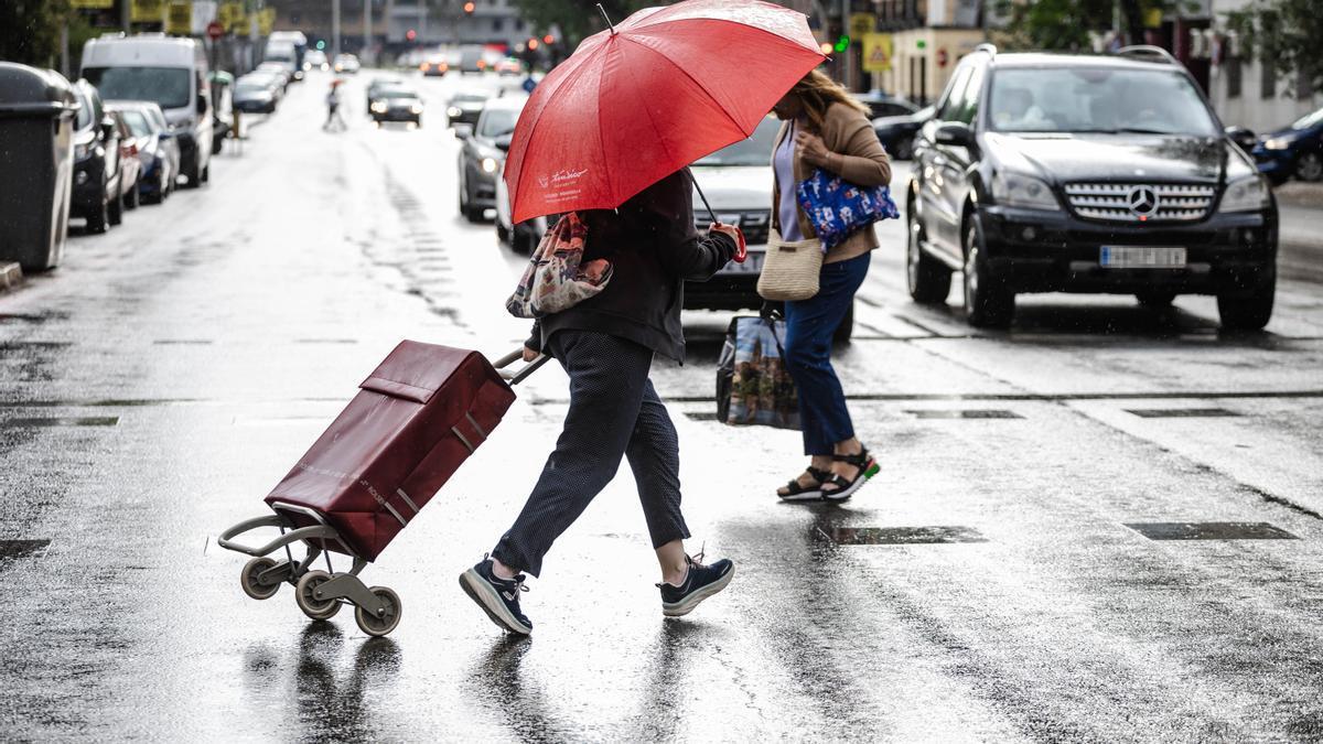 Dos personas caminan bajo la lluvia en Madrid.