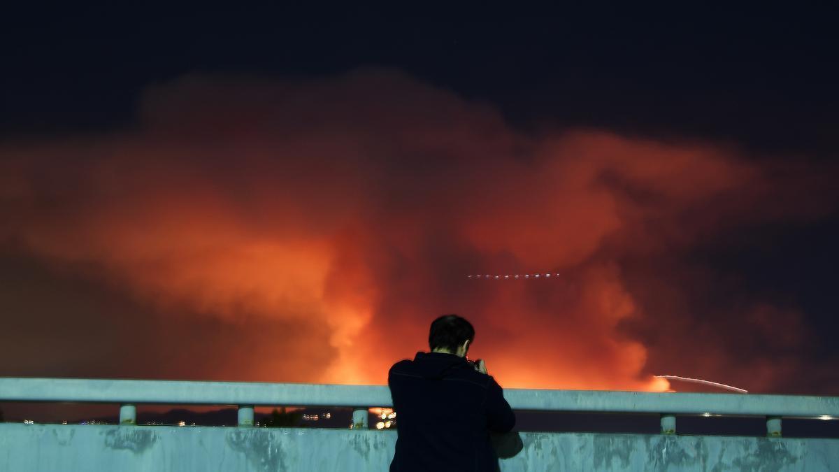 Un hombre fotografía Pacific Palisades en llamas