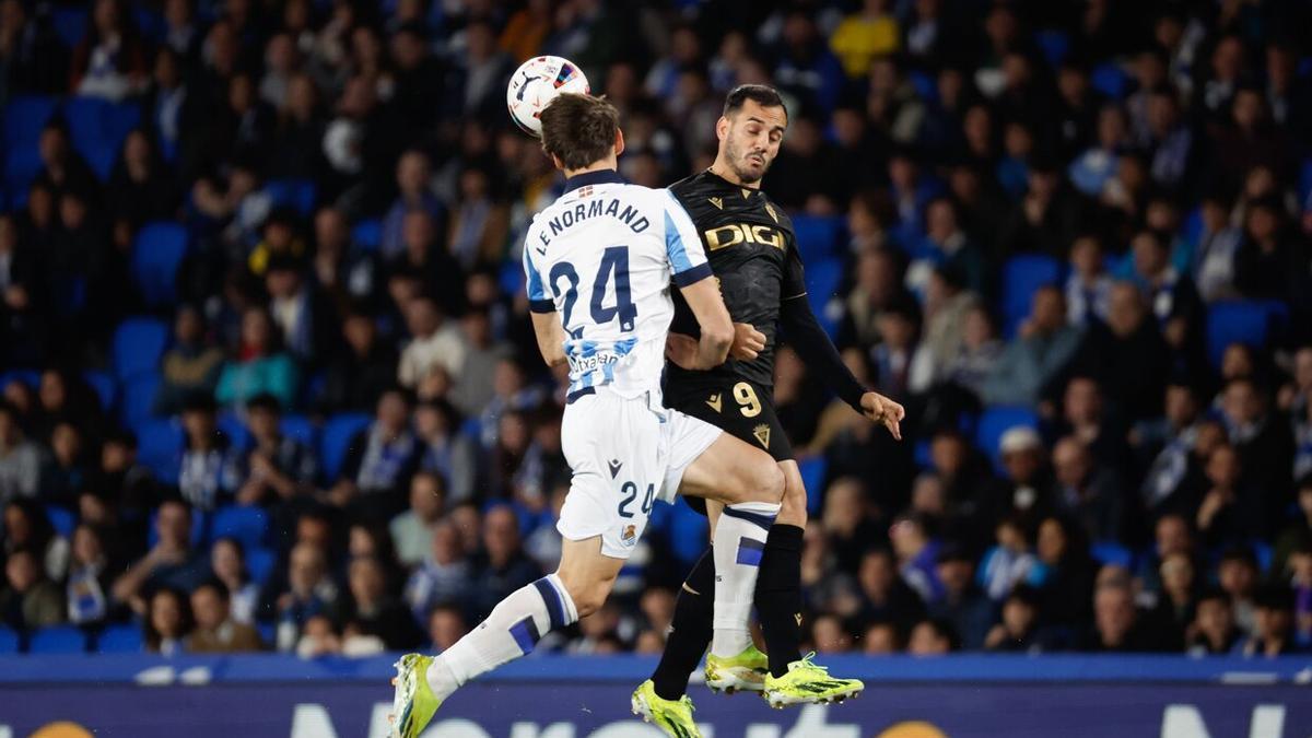 Robin Le Normand cabecea un balón en presencia del exrealista Juanmi. / EFE