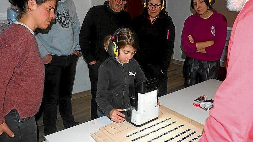 Una niña graba su nombre en madera con una fresadora.