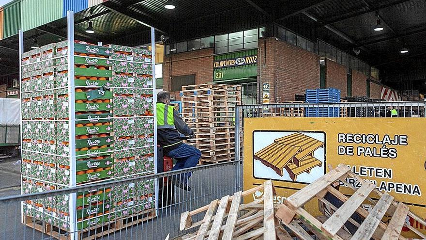 Un empleado traslada naranjas al lado de un contenedor para recoger palés de madera. | FOTO: M. B.