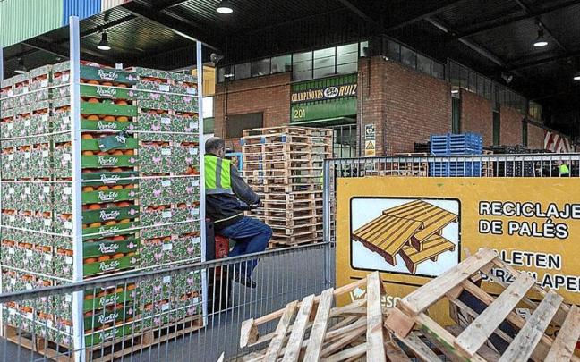 Un empleado traslada naranjas al lado de un contenedor para recoger palés de madera. | FOTO: M. B. Un empleado traslada naranjas al lado de un contenedor para recoger palés de madera. | FOTO: M. B.