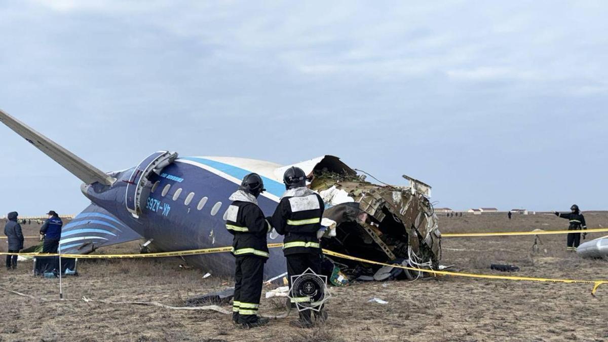 Miembros de los servicios de emergencias trabajan en el rescate de pasajeros del avión accidentado en Kazajistán.