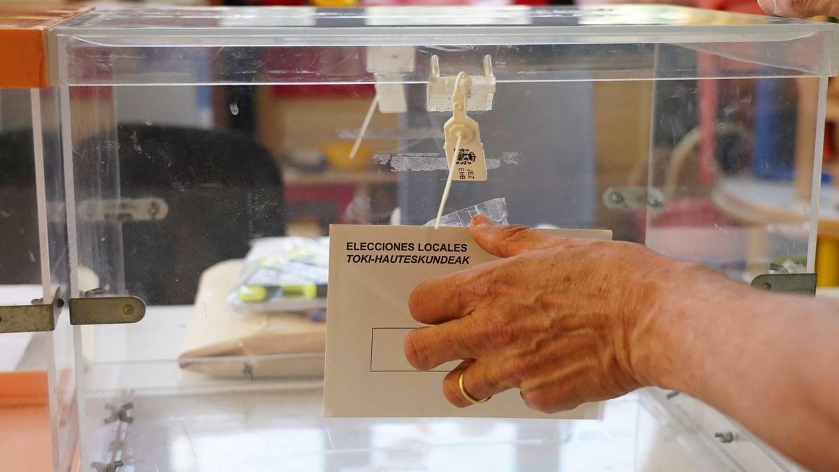 Una mujer se dispone a depositar una urna sobre la mesa de un colegio electoral en el transcurso de los preparativos para este pasado 28-M.